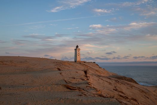 Lokken, Denmark - July 15, 2019: Rubjerg Knude Lighthouse and sand dunes during sunset time.