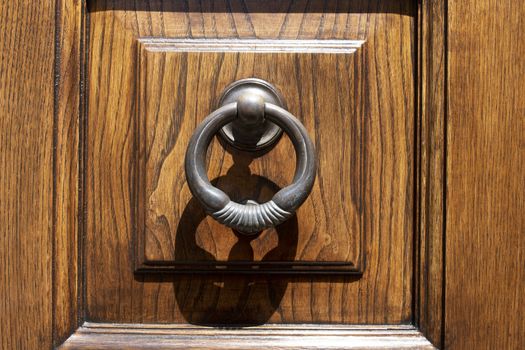 Vintage ornamented image of ancient door knocker on a wooden door.