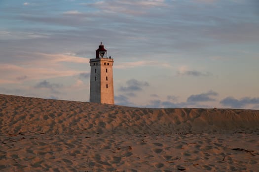 Lokken, Denmark - July 15, 2019: Rubjerg Knude Lighthouse and sand dunes during sunset time.