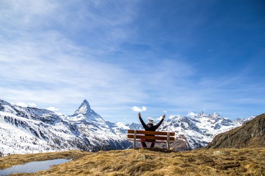 An unrecognisable man on a bench with view of the famous Matterhorn.