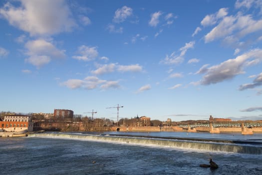 View over Garonne River in Toulouse in France with a small dam.