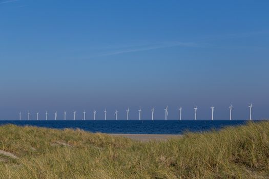 Copenhagen, Denmark - October 11, 2018: Sand dunes at Amager Beach with offshore wind power plants in the background