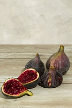 three whole purple figs and one opened on a wooden table with copy space at the background