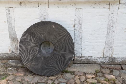 An old millstone standing on a wall.