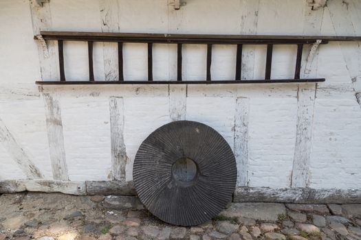 A standing millstone and hanging wooden ladder.