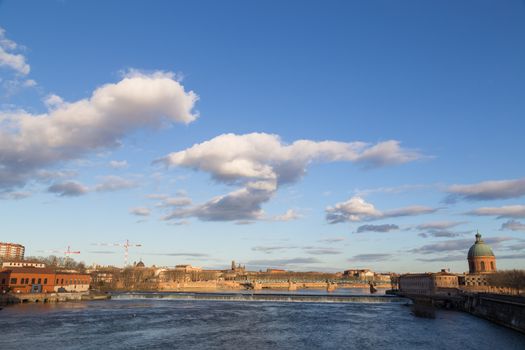 View over Garonne River in Toulouse in France with the dam and the dome of the Grave hospital.