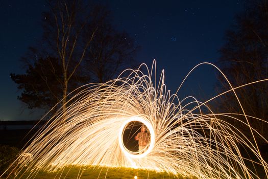 A young man performing steel wool photography.