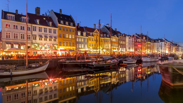 Copenhagen, Denmark - May 08, 2016: Famous Nyhavn harbor with people in bars and cafes on a summer night