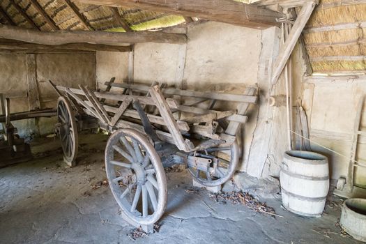 Old wooden horse-drawn cart standing inside a barn.