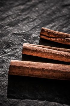 Cinnamon sticks on black stone background, food recipes