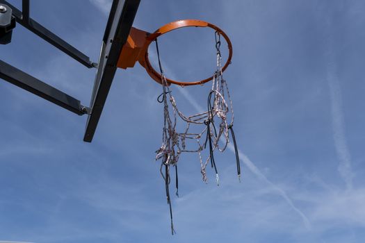 A photo from a low angle of a basketball hoop with a red ring against a cloudless warm summer sky