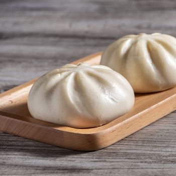 Delicious baozi, Chinese steamed meat bun is ready to eat on serving plate and steamer, close up, copy space product design concept.