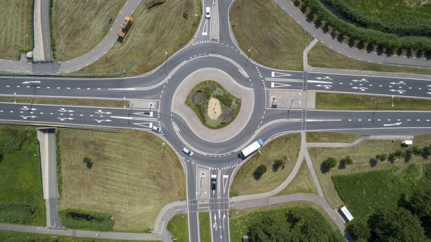 Aerial top down view of a traffic roundabout on a main road in an green urban area of the Netherlands