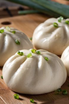 Delicious baozi, Chinese steamed meat bun is ready to eat on serving plate and steamer, close up, copy space product design concept.