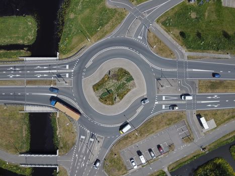 Aerial top down view of a traffic roundabout on a main road in an green urban area of the Netherlands