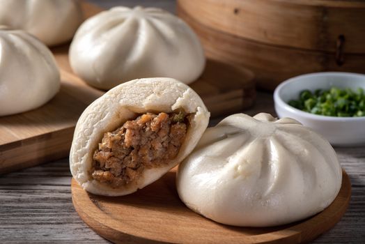 Delicious baozi, Chinese steamed meat bun is ready to eat on serving plate and steamer, close up, copy space product design concept.