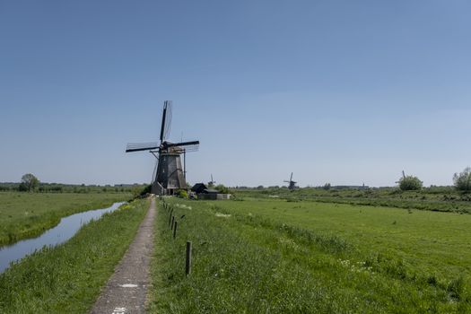 Landscape with beautiful traditional dutch windmills near the water canals with blue sky and clouds reflection in water. Kinderdijk