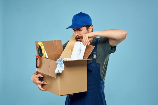 Worker man in uniform box tools construction blue background. High quality photo