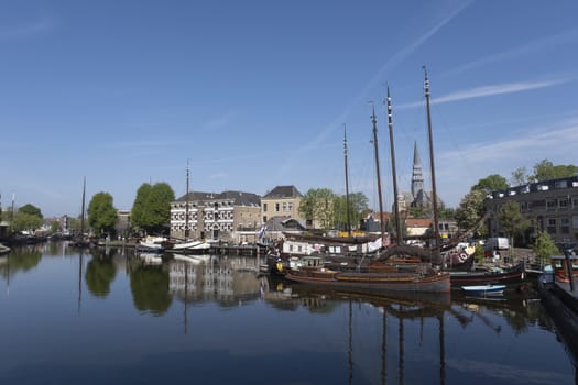Museum harbor and Turfsingelgracht in Gouda with historic boats, De Roode Leeuw flour mill and the Gouwekerk