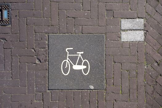 A high angle closeup shot of a bicycle sign painted on the brick stones in the street