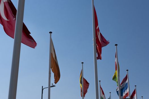Flags waving in the wind on flagpoles equal distant apart against a blue sky