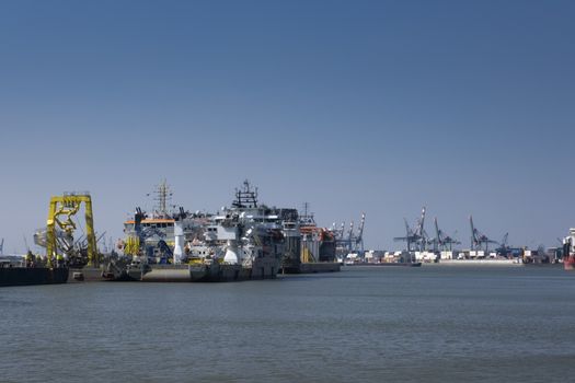 Huge cranes and ships anchored at harbor. International commercial port, city of Rotterdam background. Logistics business