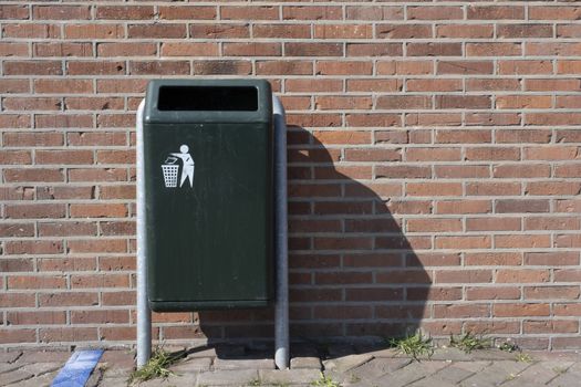 Modern green Metallic trash bin in a sunny urban environment