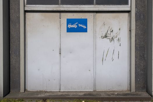 old metal warehouse door, hangar with tow away sign