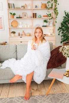 Young beautiful girl having a cup of coffee on a couch. Miracle relaxed morning concept