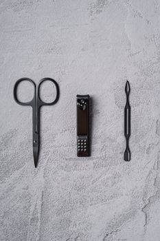 Set of manicure, pedicure tools and accessories in row, stone concrete background, top view