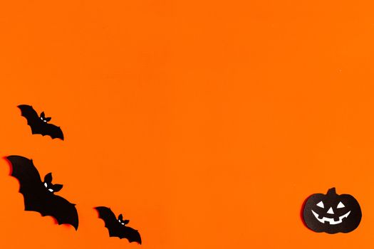 silhouettes of bats and pumpkins made of black paper on an orange background, Halloween concept, ready-made layout with space for text, copy space. Flat lay for your design.