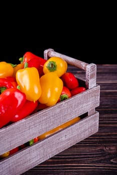 Fresh colored bell peppers on a wooden table on a rustic wooden background, selective focus