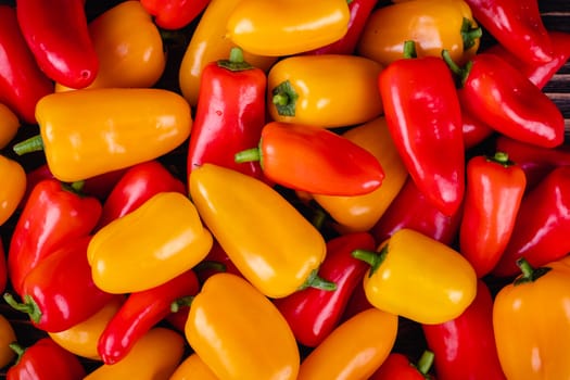 Fresh colored bell peppers on a wooden table on a rustic wooden background, selective focus