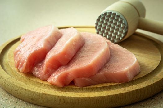 Pork loin on a wooden board and meat mallet