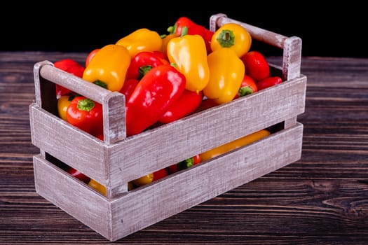 Fresh colored bell peppers on a wooden table on a rustic wooden background, selective focus