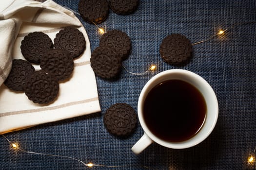 Brown cookies lying next to the coffee in a white cup