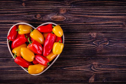 Fresh colored bell peppers on a wooden table on a rustic wooden background, selective focus