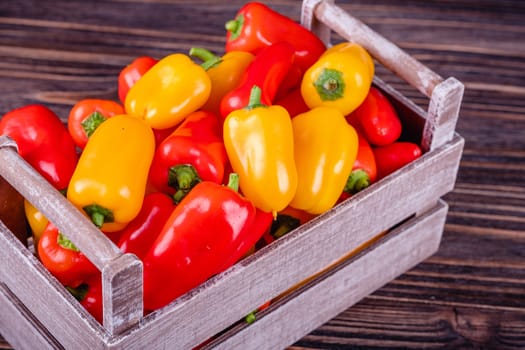 Fresh colored bell peppers on a wooden table on a rustic wooden background, selective focus