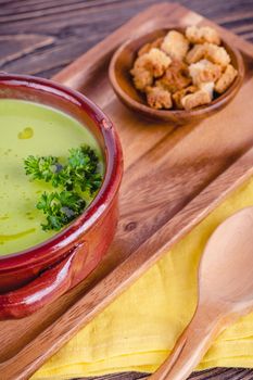 Fresh asparagus creamy soup and ingredients on wooden table on rustic wooden background, selective focus