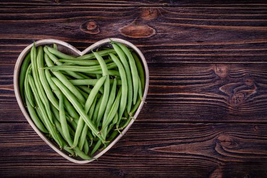 Fresh green beans on wooden table on rustic wooden background.