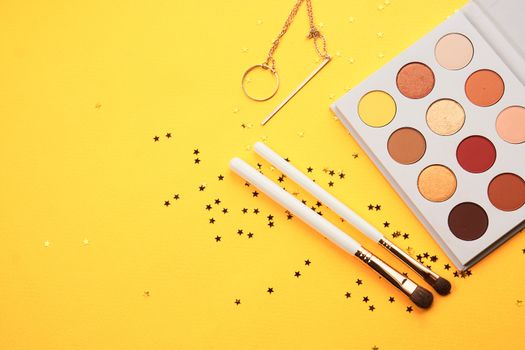 Professional eyeshadows and makeup brushes on a yellow background make-up decoration. High quality photo