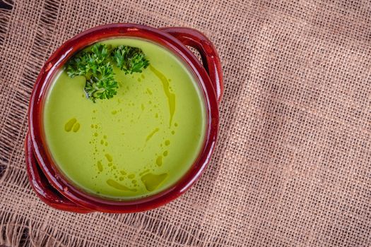 Fresh asparagus creamy soup and ingredients on wooden table on rustic wooden background, selective focus