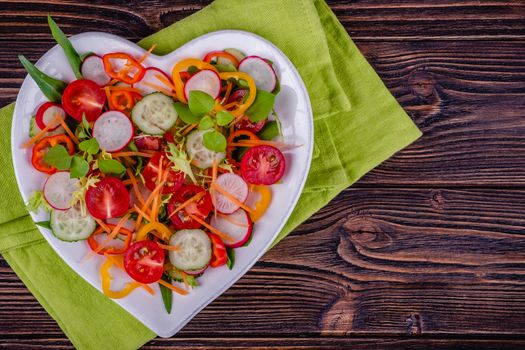 Fresh chopped vegetables on a plate on a wooden table on a rustic wooden background, selective focus