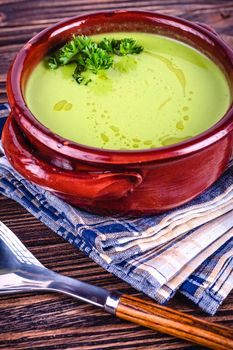 Fresh asparagus creamy soup and ingredients on wooden table on rustic wooden background, selective focus