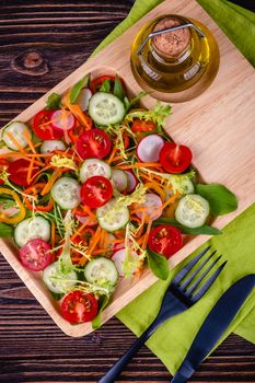 Fresh chopped vegetables on a plate on a wooden table on a rustic wooden background, selective focus