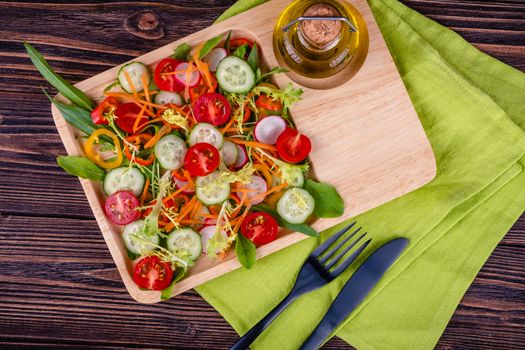 Fresh chopped vegetables on a plate on a wooden table on a rustic wooden background, selective focus