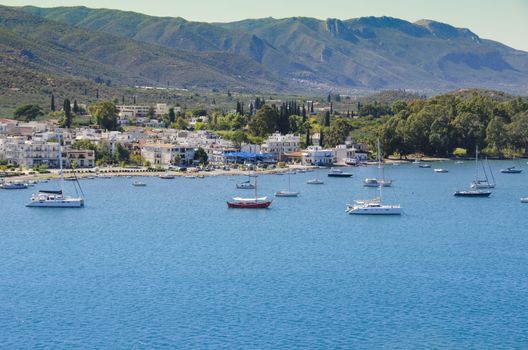 boats anchored in the waters of the saronic sea in front of the capital of the island of pores and bottom with the mountains of the island