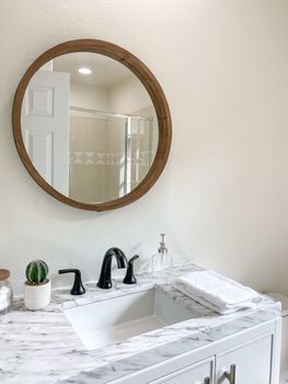 Round mirror over sink with marble counter top in stylish bathroom interior.