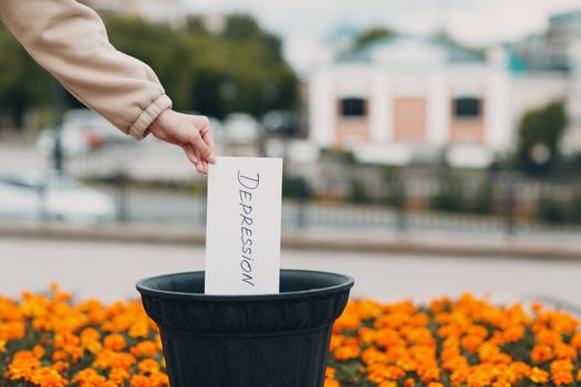 Woman throws sheet with word depression into trash can. Psychology help.