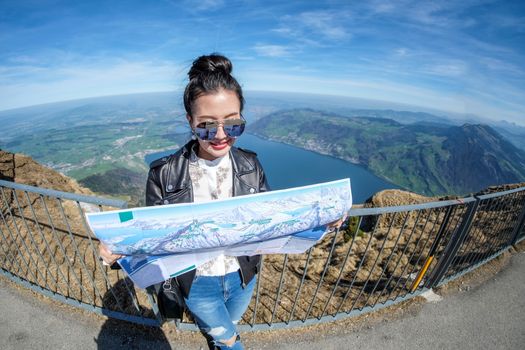 Young female tourist looking map at Rigi mountain in Switzerland with a magnificent panoramic view of Swiss alps